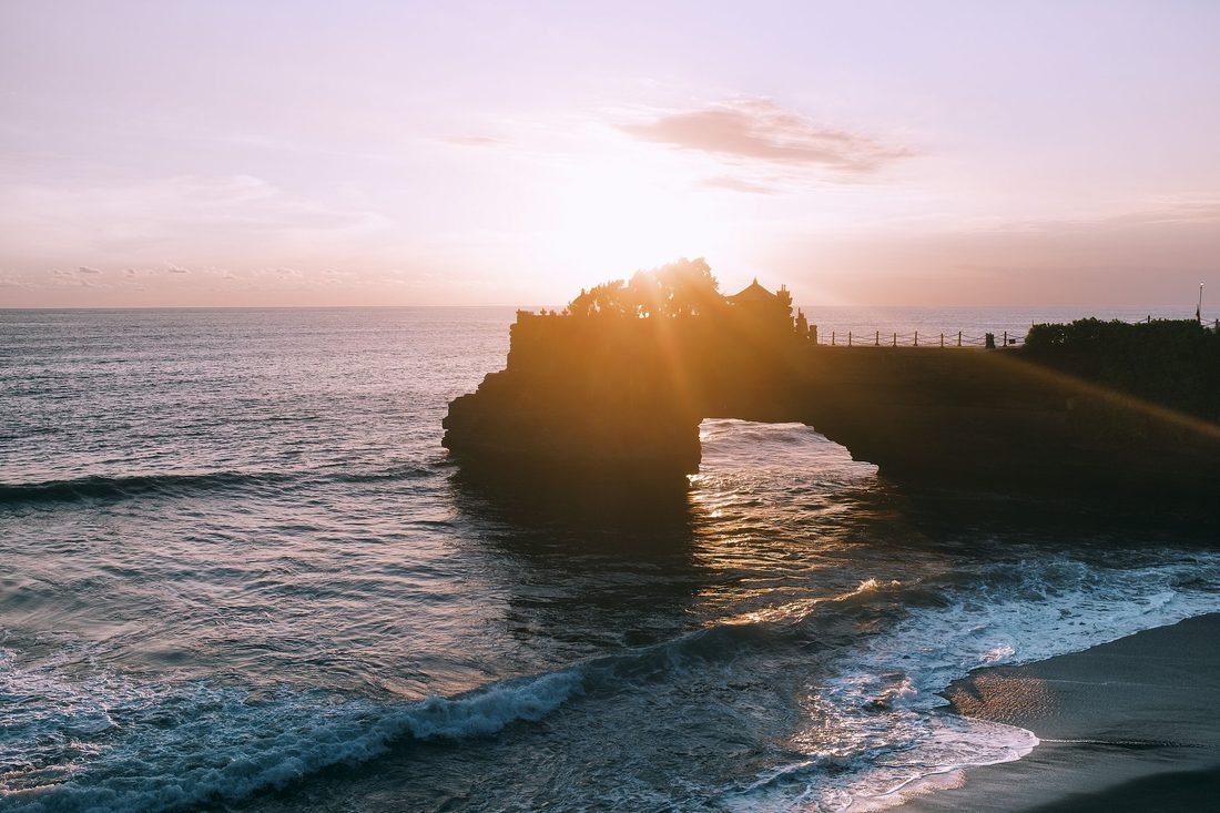 The Batu Bolong rock arch standing in the sea at sunset near Tanah Lot, Bali